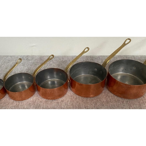 151 - A VERY GOOD SET OF SEVEN COPPER SAUCEPANS, each with heavy brass handles.