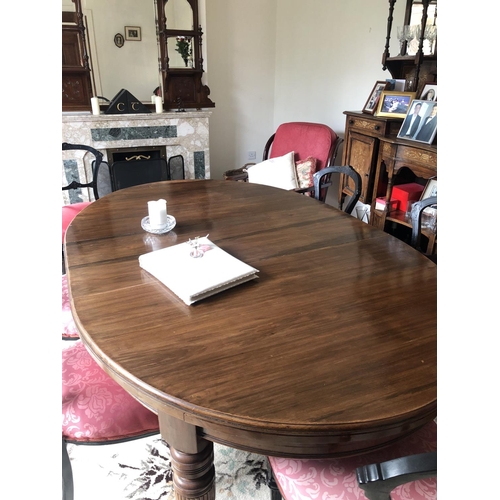 214 - A MAHOGANY OVAL SHAPED EXTENDABLE DINING TABLE, raised on turned & carved legs, sitting on castors. ... 