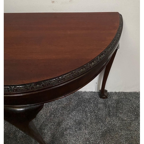 227 - A GOOD QUALITY DEMI-LUNE SHAPED MAHOGANY FOLD OVER CARD TABLE, with carved foliage detail to the fro... 