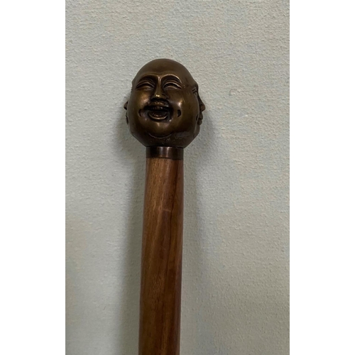 228 - AN UNUSUAL WALKING CANE/STICK; with four face design to the handle, tapered end. 92cm tall.