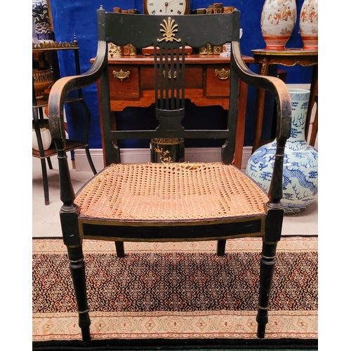 74 - A REGENCY EBONISED CANE-SEAT ARMCHAIR, with gilt mount detail to the curved crest rail and a lyre st... 