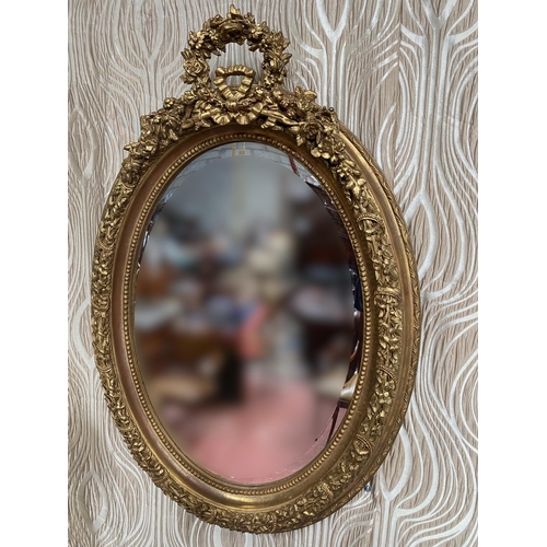 101 - A LOVELY PAIR OF GILT WALL MIRRORS, oval in shape with frames decorated all over with shamrocks & fo... 