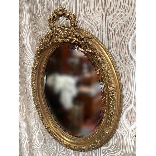 101 - A LOVELY PAIR OF GILT WALL MIRRORS, oval in shape with frames decorated all over with shamrocks & fo... 