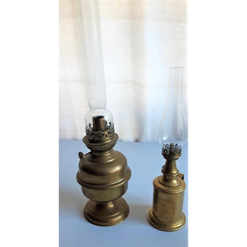 129 - TWO BRASS OIL LAMPS with clear glass chimney’s, one with a wall bracket. 45cm & 31cm tall respective... 