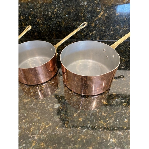 141 - A VERY GOOD SET OF FOUR COPPER SAUCEPANS, with brass handles.