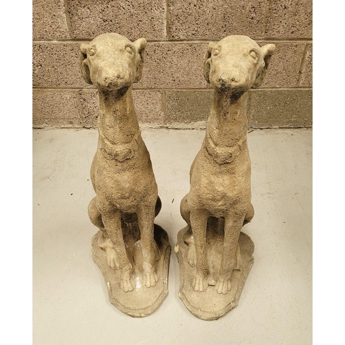 100 - A PAIR OF STONE COMPOSITE GARDEN ORNAMENTS IN THE FORM OF TWO SEATED HOUNDS, each with a collar. Dim... 