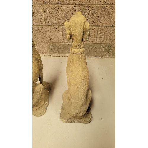 100 - A PAIR OF STONE COMPOSITE GARDEN ORNAMENTS IN THE FORM OF TWO SEATED HOUNDS, each with a collar. Dim... 