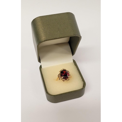 31 - A BEAUTIFUL YELLOW GOLD & GARNET RING, with an open work edge that holds the large oval shaped garne... 