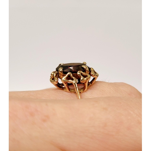 31 - A BEAUTIFUL YELLOW GOLD & GARNET RING, with an open work edge that holds the large oval shaped garne... 