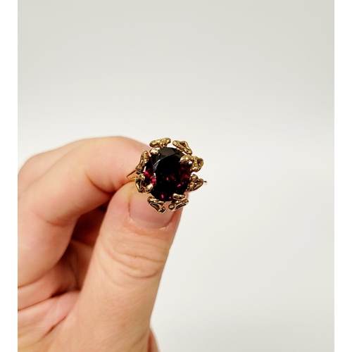 31 - A BEAUTIFUL YELLOW GOLD & GARNET RING, with an open work edge that holds the large oval shaped garne... 