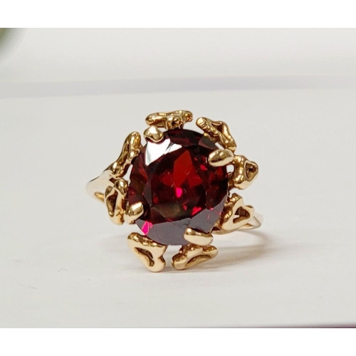 31 - A BEAUTIFUL YELLOW GOLD & GARNET RING, with an open work edge that holds the large oval shaped garne... 