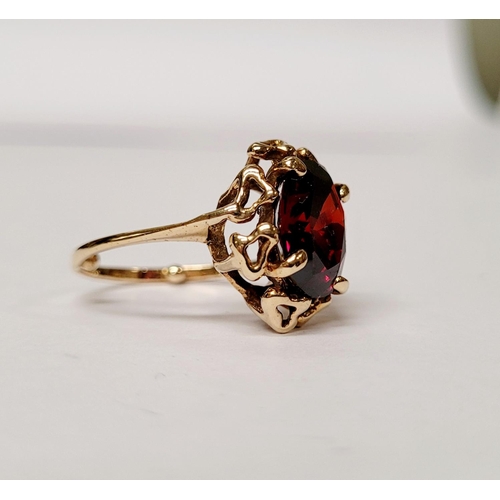 31 - A BEAUTIFUL YELLOW GOLD & GARNET RING, with an open work edge that holds the large oval shaped garne... 
