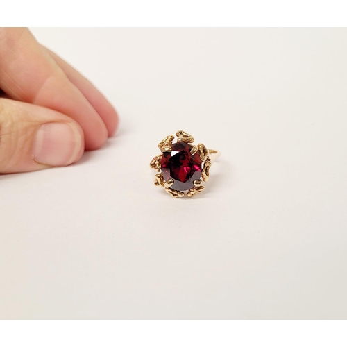 31 - A BEAUTIFUL YELLOW GOLD & GARNET RING, with an open work edge that holds the large oval shaped garne... 