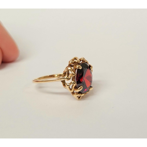 31 - A BEAUTIFUL YELLOW GOLD & GARNET RING, with an open work edge that holds the large oval shaped garne... 