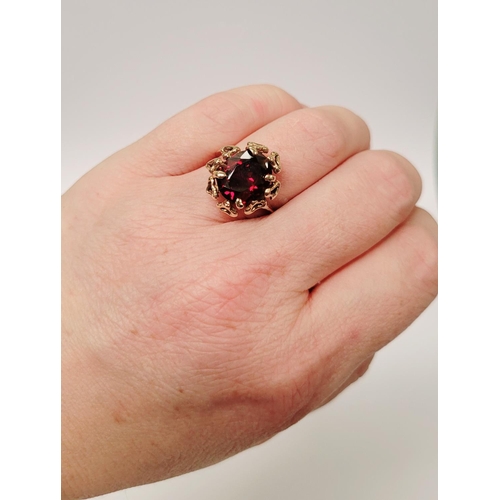 31 - A BEAUTIFUL YELLOW GOLD & GARNET RING, with an open work edge that holds the large oval shaped garne... 