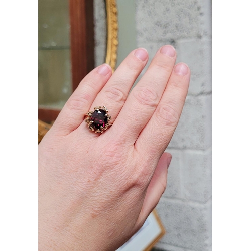 31 - A BEAUTIFUL YELLOW GOLD & GARNET RING, with an open work edge that holds the large oval shaped garne... 