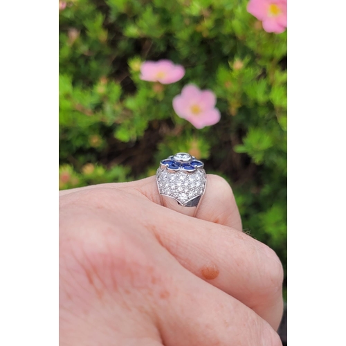 82 - A PRETTY 18CT WHITE GOLD SAPPHIRE & DIAMOND FLORAL CLUSTER / DRESS BOMBE SHAPED RING, the curved set... 