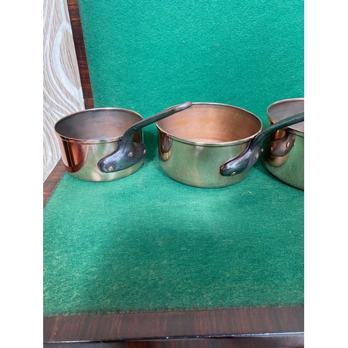 106 - A GOOD QUALITY SET OF FIVE GRADUATED COPPER SAUCEPANS, with heavy steel handles. In good, clean cond... 