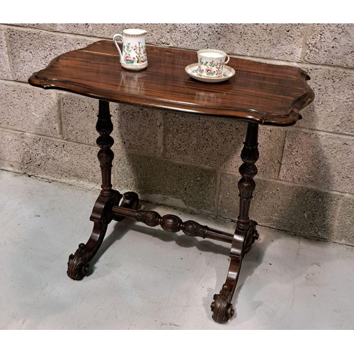 225 - A SERPENTINE SHAPED SIDE / LAMP TABLE RAISED ON A FINELY CARVED POD SUPPORT, a pair of columns sit u... 