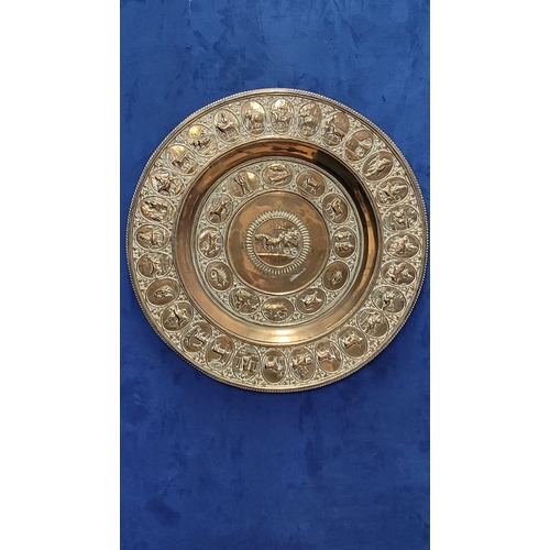 229 - TWO POLISHED BRASS DECORATIVE TRAYS, (i) One a brass zodiac charger/tray; decorated with figures in ... 