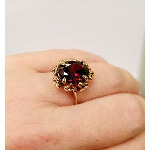 78 - A BEAUTIFUL YELLOW GOLD & GARNET RING, with an open work edge that holds the large oval shaped garne... 
