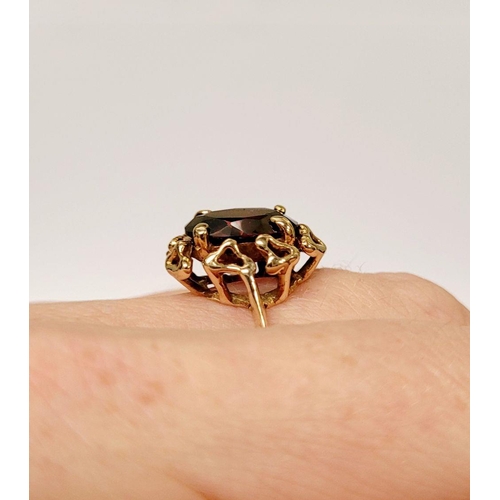 78 - A BEAUTIFUL YELLOW GOLD & GARNET RING, with an open work edge that holds the large oval shaped garne... 