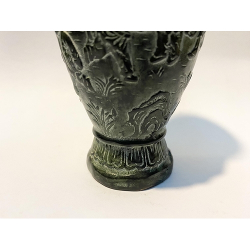 102 - A CHINESE BRONZE URN VASE, with textured fluted design to rim and base, figural design to body in re... 