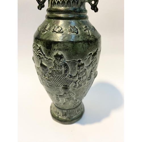 102 - A CHINESE BRONZE URN VASE, with textured fluted design to rim and base, figural design to body in re... 