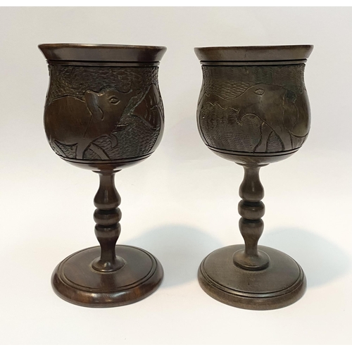 126 - A PAIR OF HARDWOOD CARVED GOBLETS, both with carved scenes to body depicting elephants and with turn... 