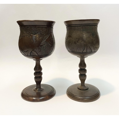 126 - A PAIR OF HARDWOOD CARVED GOBLETS, both with carved scenes to body depicting elephants and with turn... 