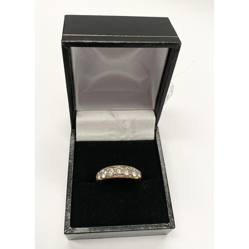 141 - A SPARKLING 18CT YELLOW GOLD SEVEN STONE DIAMOND BAND, with seven round cut diamonds in 18ct yellow ... 