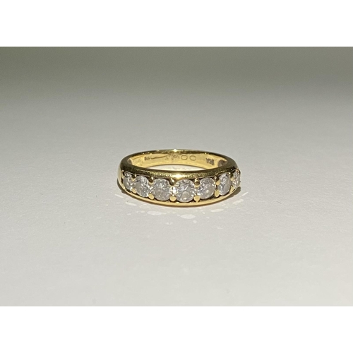 141 - A SPARKLING 18CT YELLOW GOLD SEVEN STONE DIAMOND BAND, with seven round cut diamonds in 18ct yellow ... 