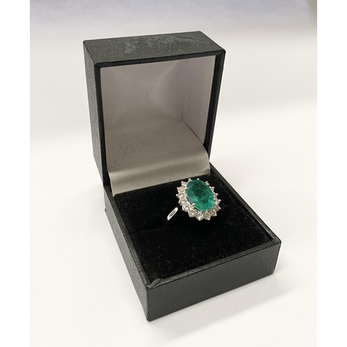 142 - A FANTASTIC 18CT WHITE GOLD EMERALD AND DIAMOND CLUSTER RING, with central vibrant oval cut emerald ... 