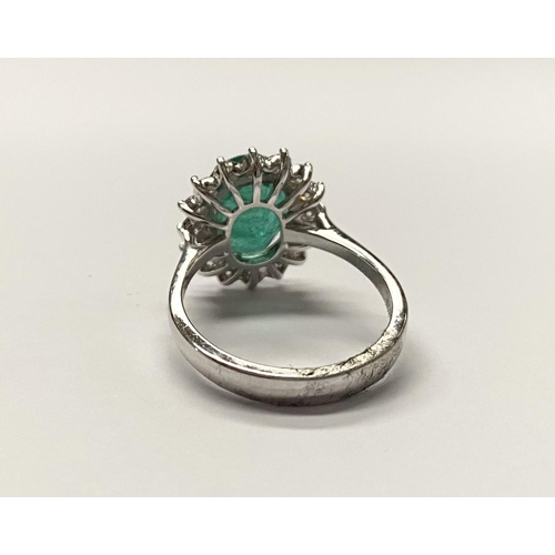 142 - A FANTASTIC 18CT WHITE GOLD EMERALD AND DIAMOND CLUSTER RING, with central vibrant oval cut emerald ... 