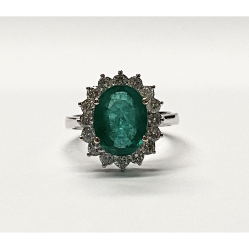 142 - A FANTASTIC 18CT WHITE GOLD EMERALD AND DIAMOND CLUSTER RING, with central vibrant oval cut emerald ... 