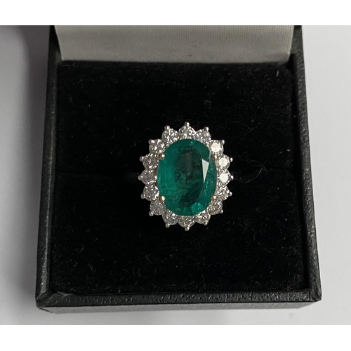 142 - A FANTASTIC 18CT WHITE GOLD EMERALD AND DIAMOND CLUSTER RING, with central vibrant oval cut emerald ... 