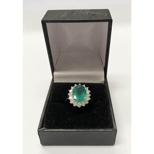 142 - A FANTASTIC 18CT WHITE GOLD EMERALD AND DIAMOND CLUSTER RING, with central vibrant oval cut emerald ... 