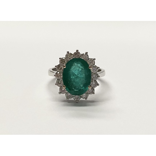 142 - A FANTASTIC 18CT WHITE GOLD EMERALD AND DIAMOND CLUSTER RING, with central vibrant oval cut emerald ... 