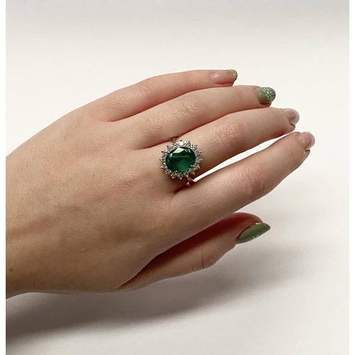 142 - A FANTASTIC 18CT WHITE GOLD EMERALD AND DIAMOND CLUSTER RING, with central vibrant oval cut emerald ... 