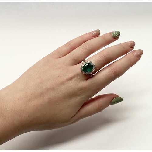 142 - A FANTASTIC 18CT WHITE GOLD EMERALD AND DIAMOND CLUSTER RING, with central vibrant oval cut emerald ... 