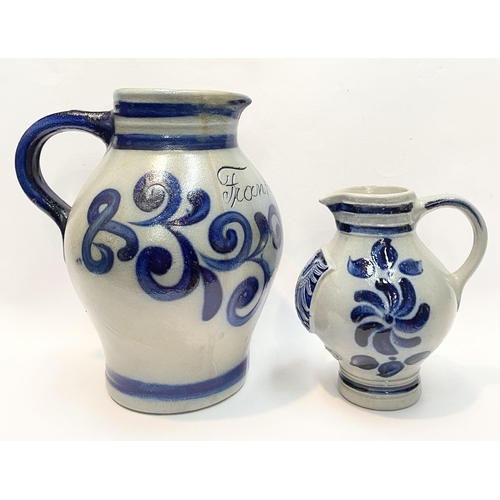 236 - TWO GERMAN SALT GLAZED STONEWARE JUGS, (i) larger pitcher jug with blue painted handle, double band ... 