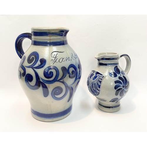 236 - TWO GERMAN SALT GLAZED STONEWARE JUGS, (i) larger pitcher jug with blue painted handle, double band ... 