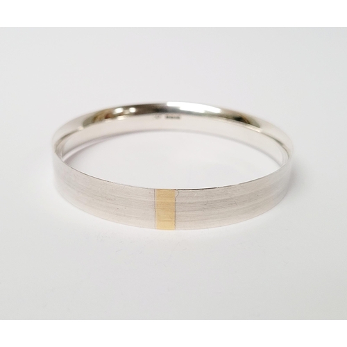 35 - A FINELY CRAFTED COX & POWER STERLING SILVER BANGLE, with brushed finish having a gold coloured stri... 