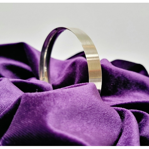 35 - A FINELY CRAFTED COX & POWER STERLING SILVER BANGLE, with brushed finish having a gold coloured stri... 