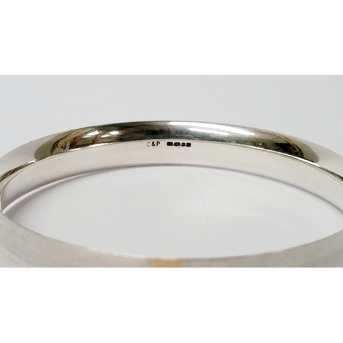 35 - A FINELY CRAFTED COX & POWER STERLING SILVER BANGLE, with brushed finish having a gold coloured stri... 