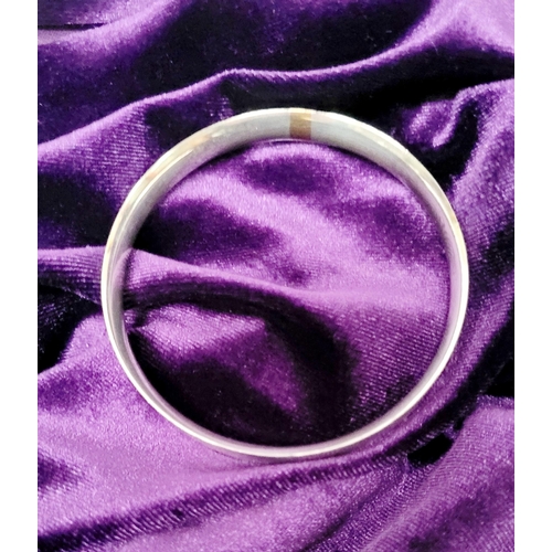 35 - A FINELY CRAFTED COX & POWER STERLING SILVER BANGLE, with brushed finish having a gold coloured stri... 