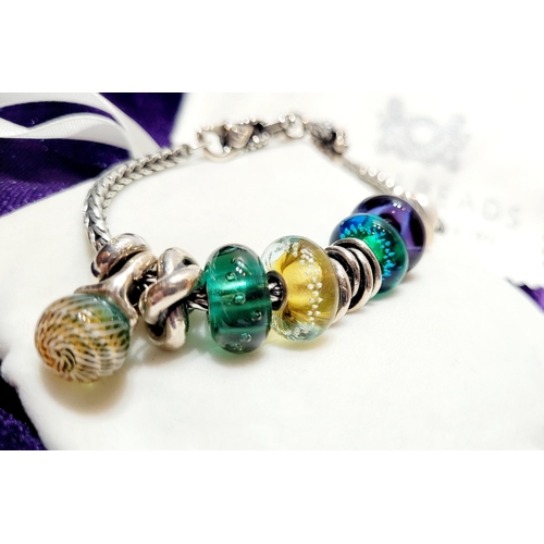 36 - A FANTASTIC TROLLBEADS STERLING SILVER BRACELET WITH CHARMS, presented in original box on a soft rib... 