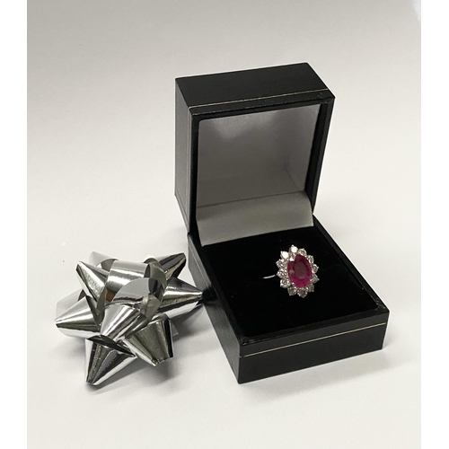 61 - AN EXCEPTIONAL 18CT WHITE GOLD RUBY AND DIAMOND CLUSTER RING, central vibrant ruby in four claw sett... 