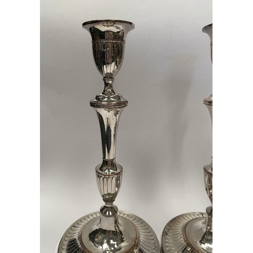 67 - A PAIR OF DECORATIVE GEORGE V STYLE SILVER PLATED CANDLESTICKS, with fluting to urn shaped sockets, ... 