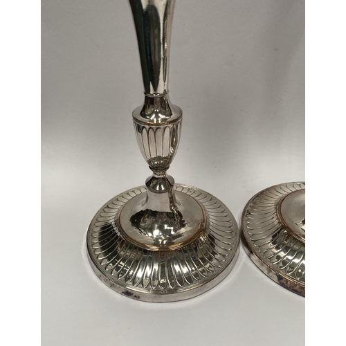 67 - A PAIR OF DECORATIVE GEORGE V STYLE SILVER PLATED CANDLESTICKS, with fluting to urn shaped sockets, ... 